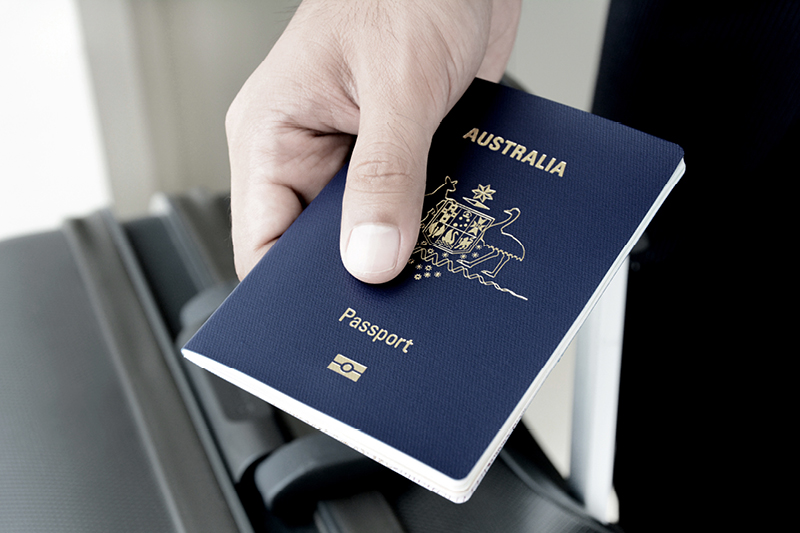 A person's hand holding a passport over a luggage case