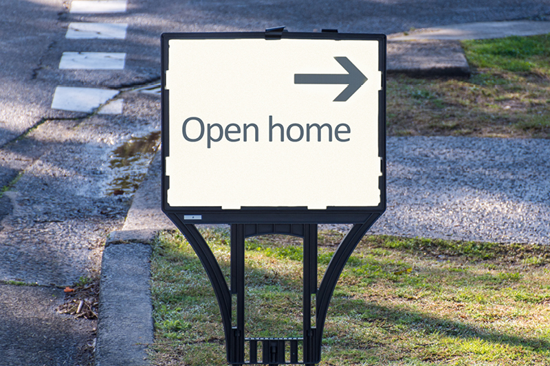 A sign on a nature strip next to a street titled Open home