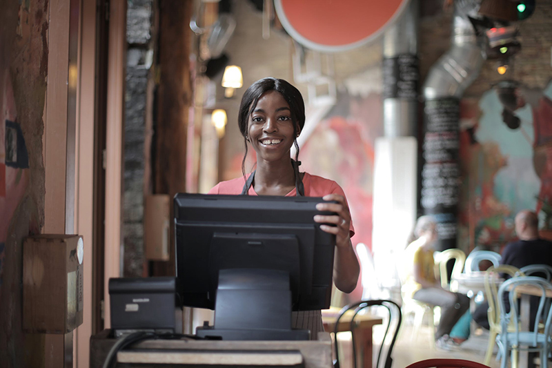 Woman standing behind point of sale computer in cafe